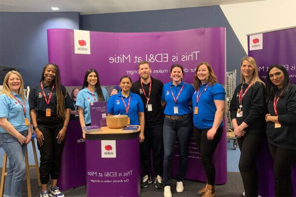 A group of Mitie colleagues in front of banners 'This is ED&I at Mitie'